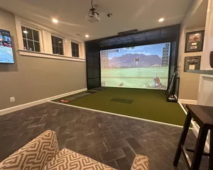Finished basement golf simulator room with a TV lounge and tile floor