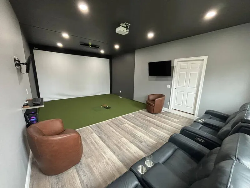 Finished basement golf simulator room with leather theater seating in a Kansas City home