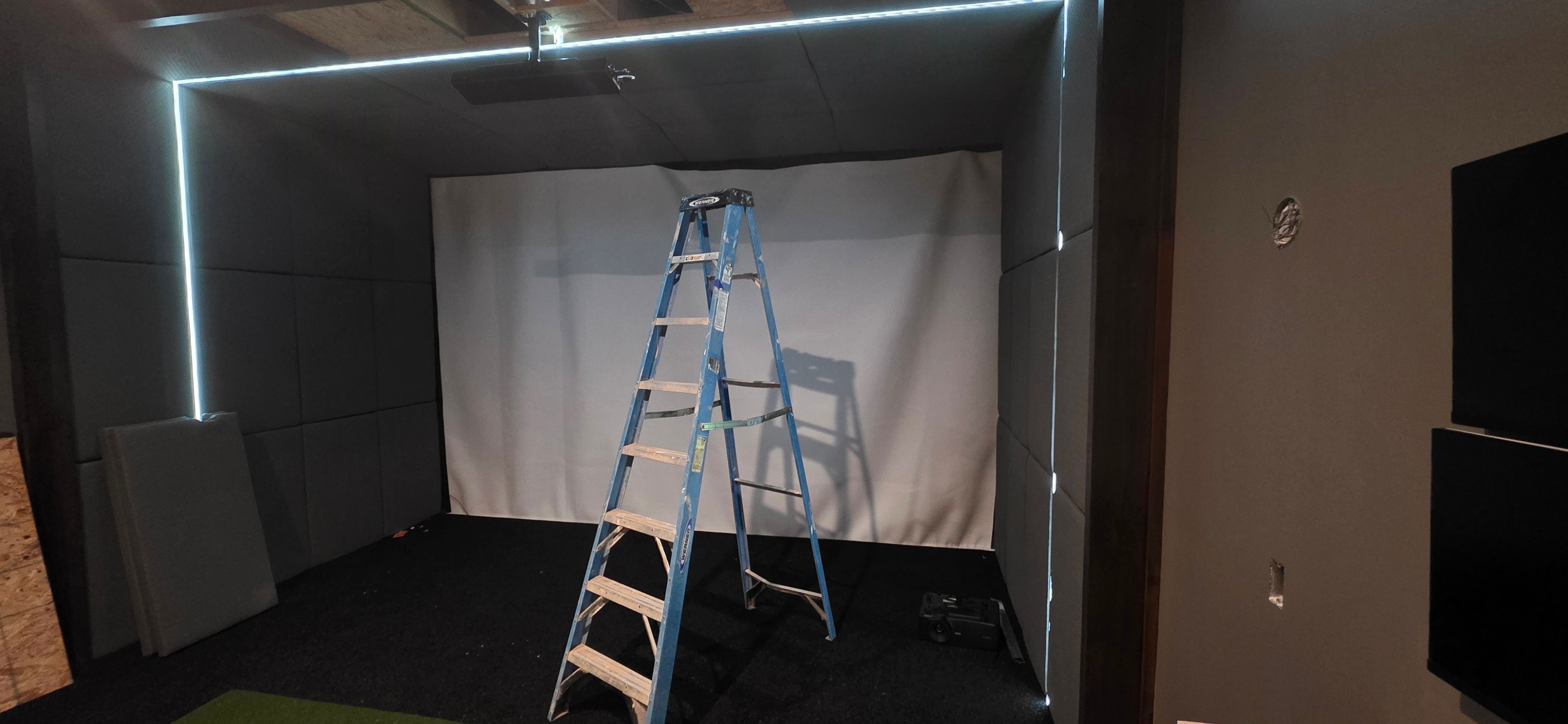 Color-matched wall pads and an LED light wrap installed around the Grain Valley golf simulator screen