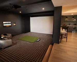 Basement golf simulator and wet bar built as a home entertainment room