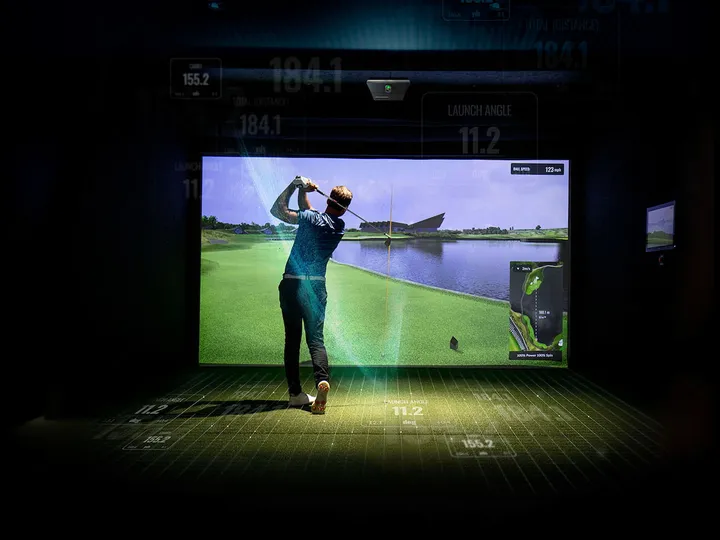 Golfer mid-swing in a finished golf simulator
