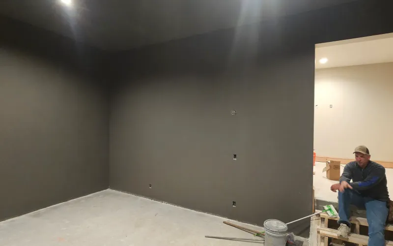 Empty basement prepped for a golf simulator with painted walls and roughed-in wiring